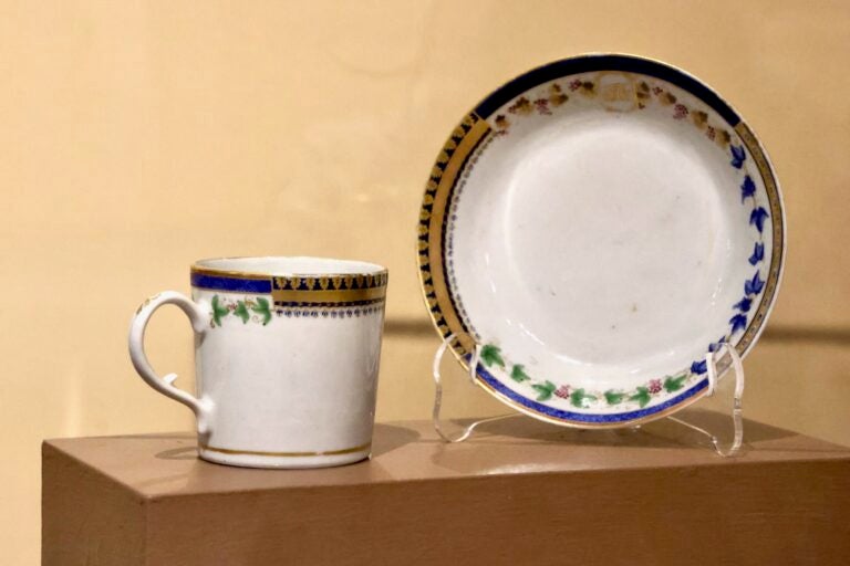 A porcelain mug and plate on display on a shelf