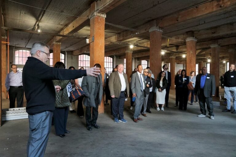 Mark Myers is pointing out features of the large empty floor while giving a tour to many people.