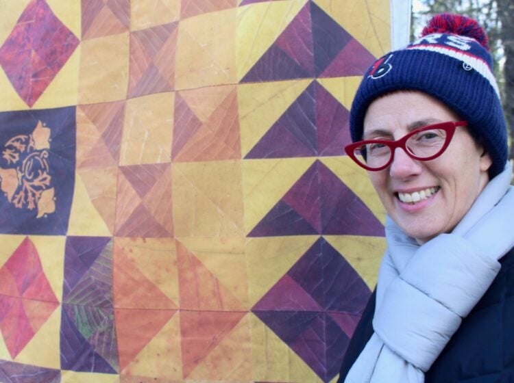 Jody Graff smiles by a quilt