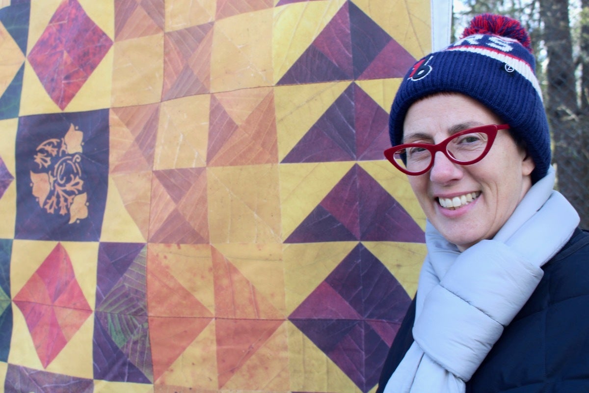 Jody Graff smiles by a quilt