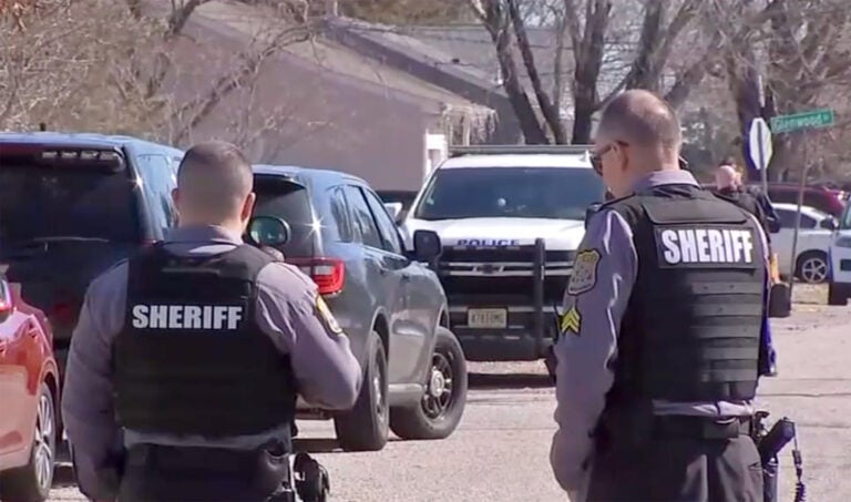 Two officers wearing Sheriff vests stand with their backs to the camera