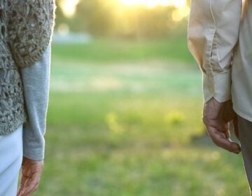 Old couple looking into future, standing apart in park indifference and break-up