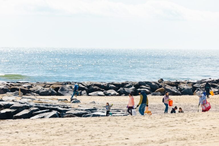 People walking along the beach picking up trash.