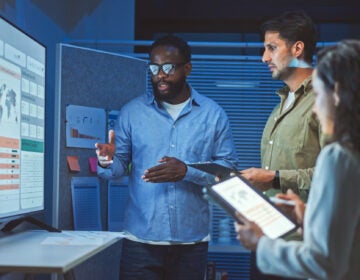 Data analytics team meeting at night. Team of multiethnic developers is meeting to review the data analysis of marketing