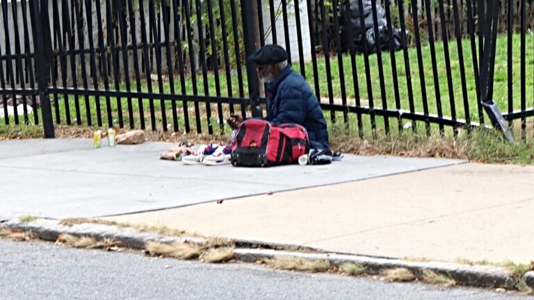 A man sits on a sidewalk