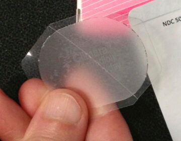 A hand holds a low-dose estrogen skin patch