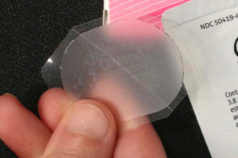 A hand holds a low-dose estrogen skin patch