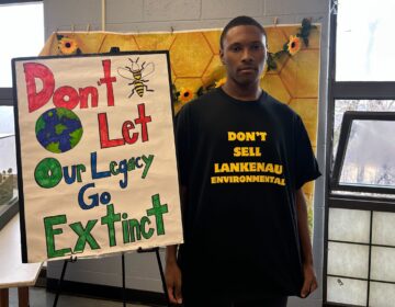 Messiah Stokes next to a sign reading Don't Let Our Legacy Go Extinct