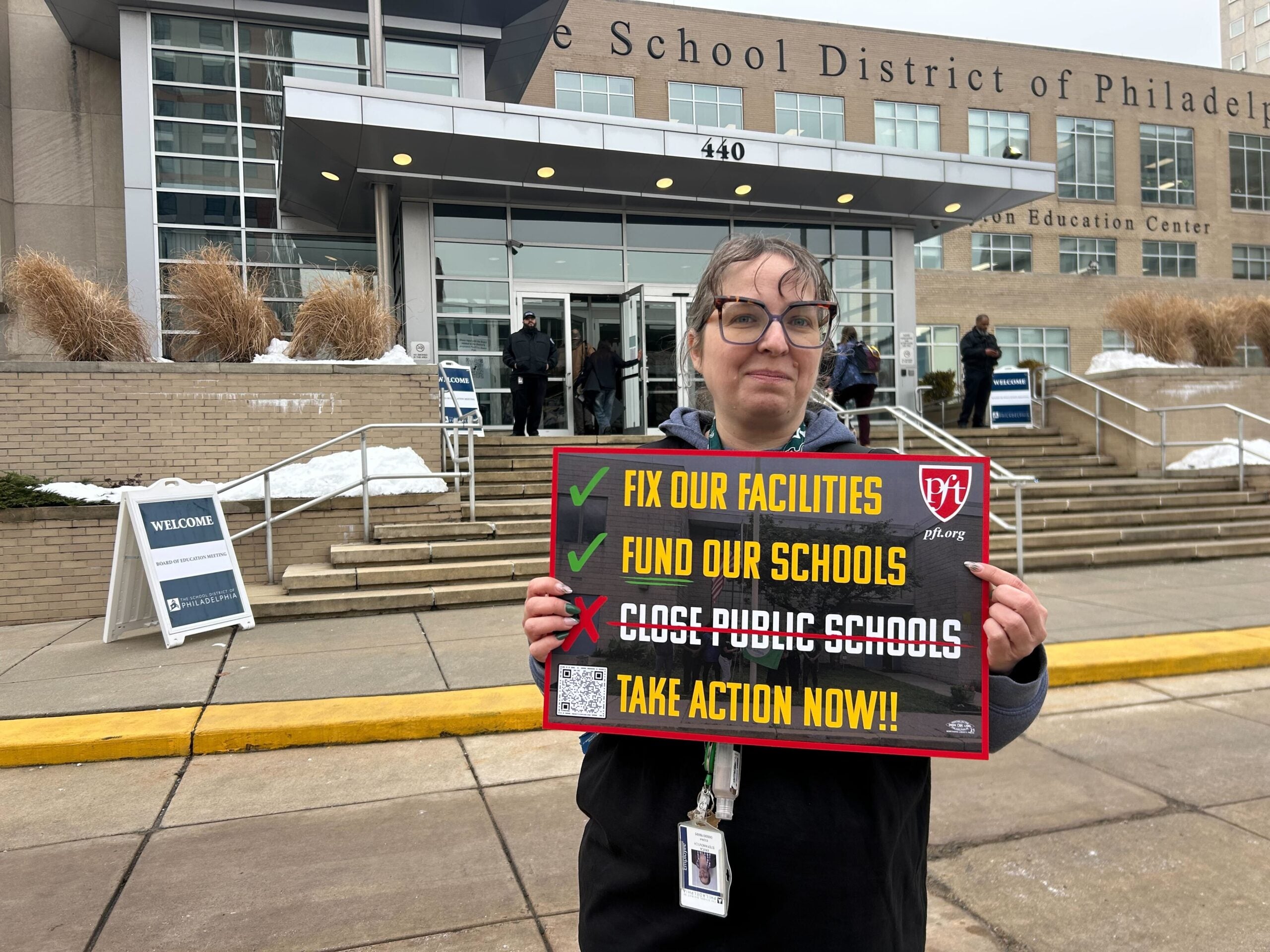 Erica Stefanovich holds a protest sign reading FIX OUR FACILITIES, FUND OUR SCHOOLS, TAKE ACTION NOW