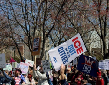 no-kings-15 People hold up signs in a protest in Philadelphia, including one that reads