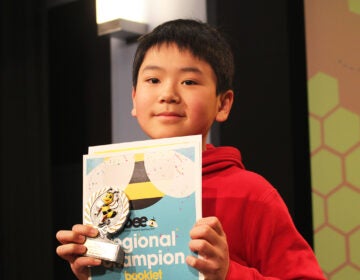 Jayden Jiang, a sixth grader at Girard Academic Music Program, holds up a sign showing he won the WHYY-Billy Penn Philadelphia Regional Spelling Bee