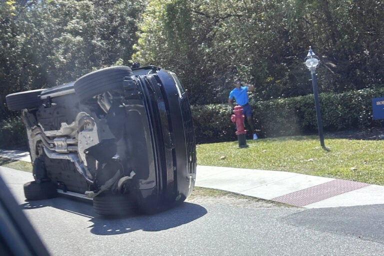 Golfer Tiger Woods stands by his overturned vehicle in Jupiter Island, Florida