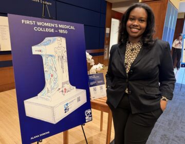 womens-medical-college-bp-031026 Artist Alana Sxmone stands next to a poster