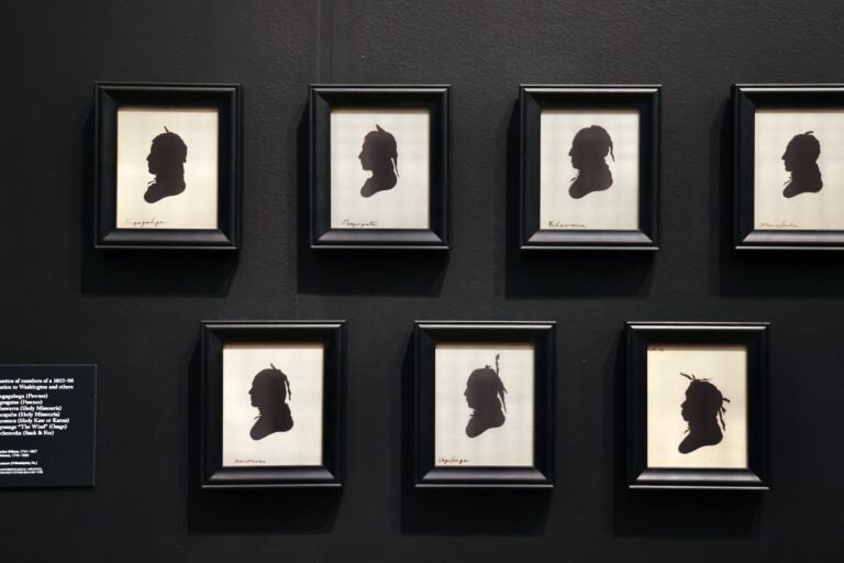 7 black silhouettes of people hanging on the wall in the exhibit
