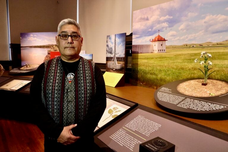 Loren Yellow Bird is posing for a photo inside the exhibit