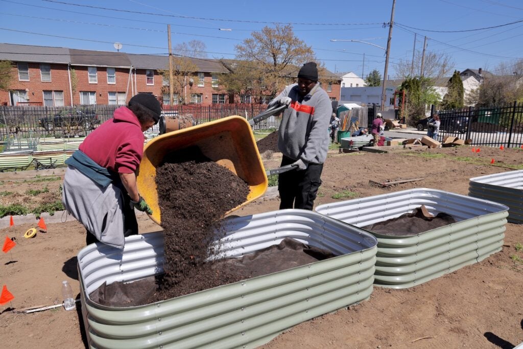 Two men unload dirt from a wheelbarrow