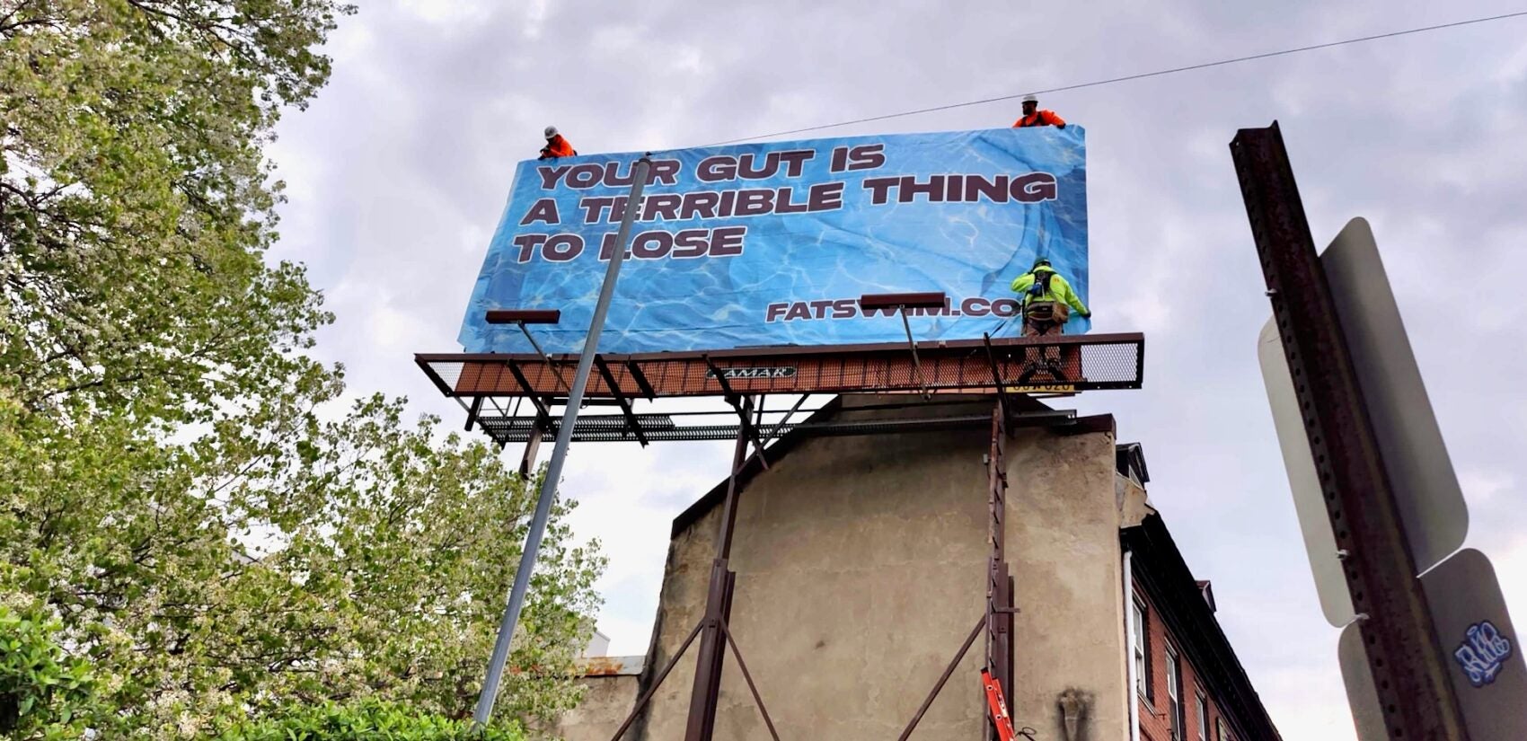 Workers install author Emma Copley Eisenberg's billboard on Fairmount Avenue