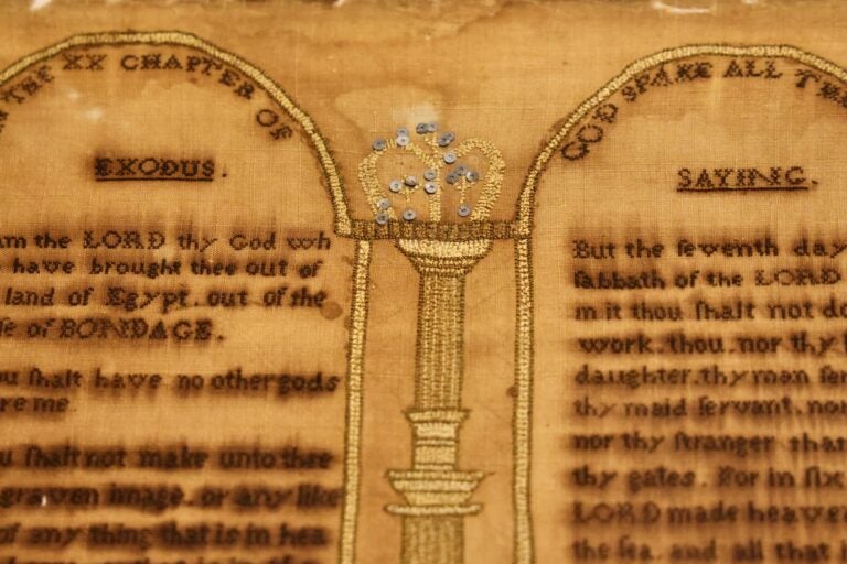 A sampler stitched by Rebecca Hendricks features the Ten Commandments and a crown