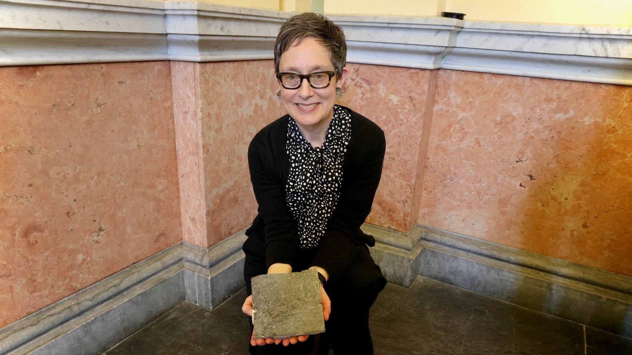 Please Touch Museum President and CEO Melissa Weiler Gerber holds a small square of the original King of Prussia marble tile used in Memorial Hall