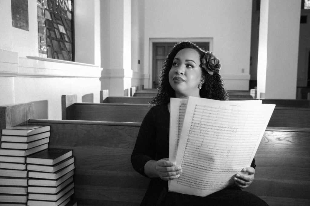 Courtney Bryan posing for a photo holding large sheet music