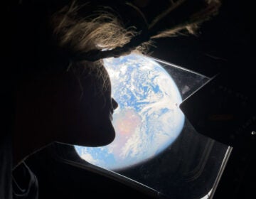 This image provided by NASA, astronaut and Artemis II mission specialist Christina Koch peers out of one of the Orion spacecraft's main cabin windows, looking back at Earth, as the crew travels towards the Moon on Thursday, April 2, 2026.  (NASA via AP)