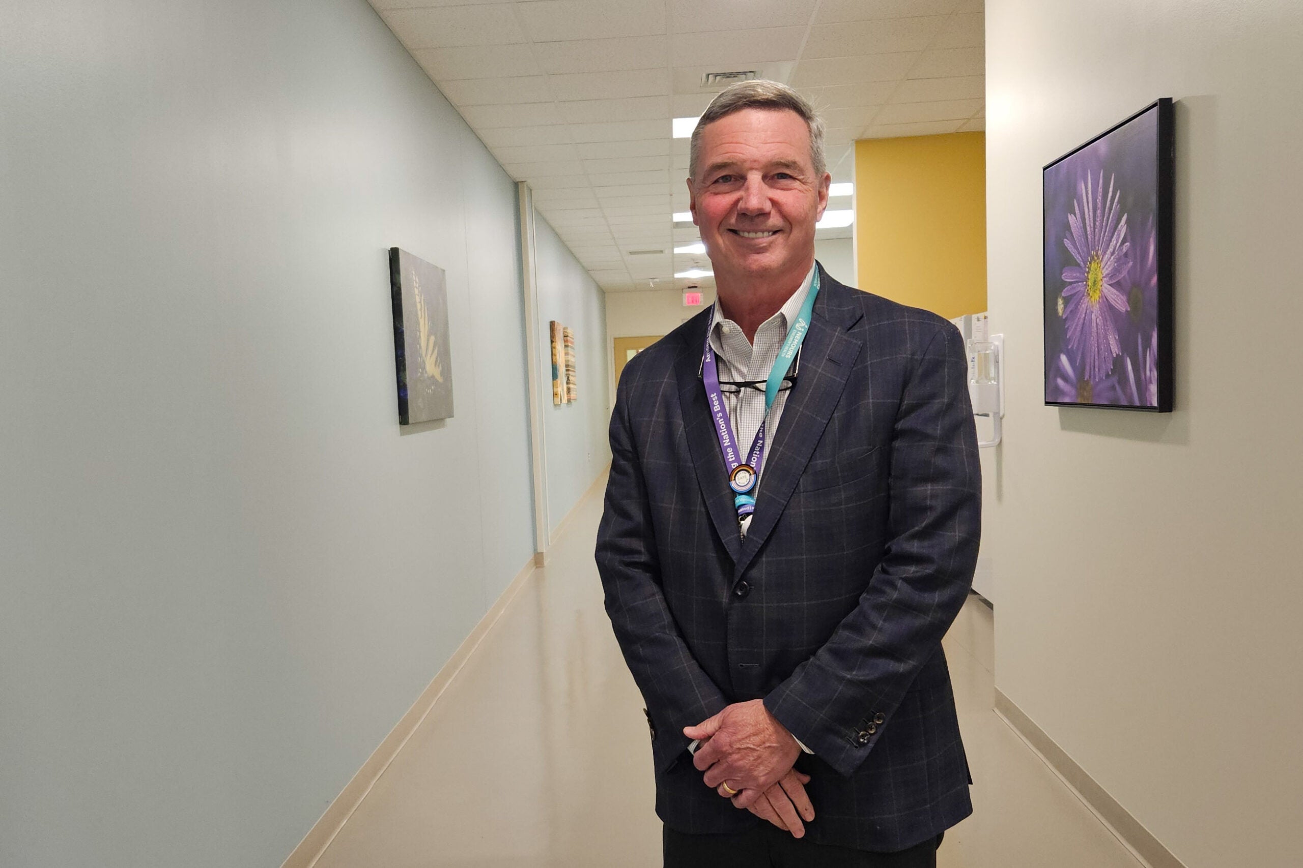 Dr. Kirk Reichard is posing for a photo in a hallway at the hospital.
