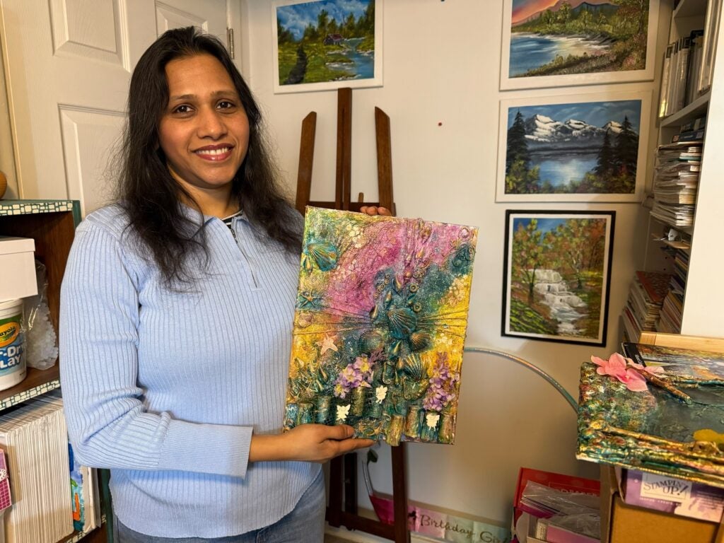 Apeksha Jain holding up a piece of her artwork