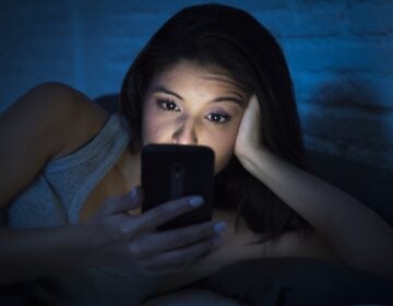 bigstock–160266668 A young woman is using her smartphone at night.
