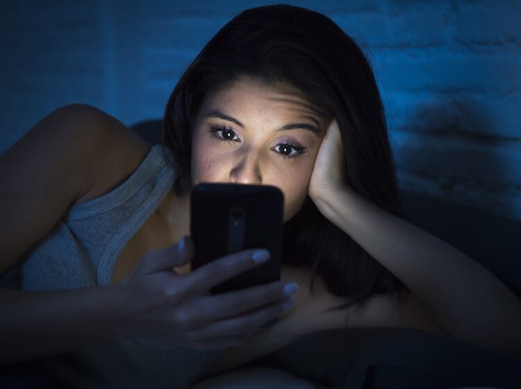 A young woman is using her smartphone at night.