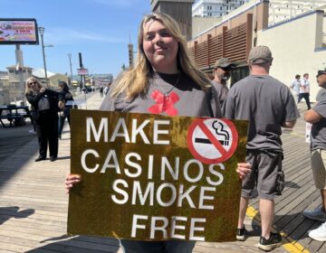 a person holds a sign reading MAKE CASINOS SMOKE FREE