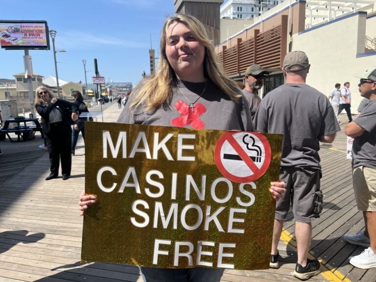 a person holds a sign reading MAKE CASINOS SMOKE FREE