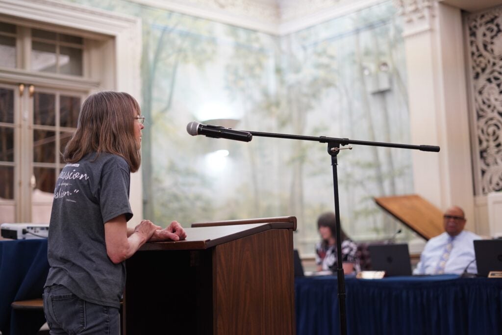 A person speaks at a podium to ask a question of the commissioners.