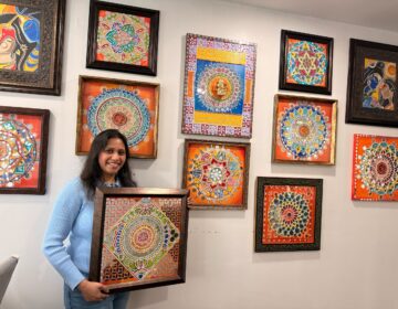Apeksha Jain holding up a piece of her artwork