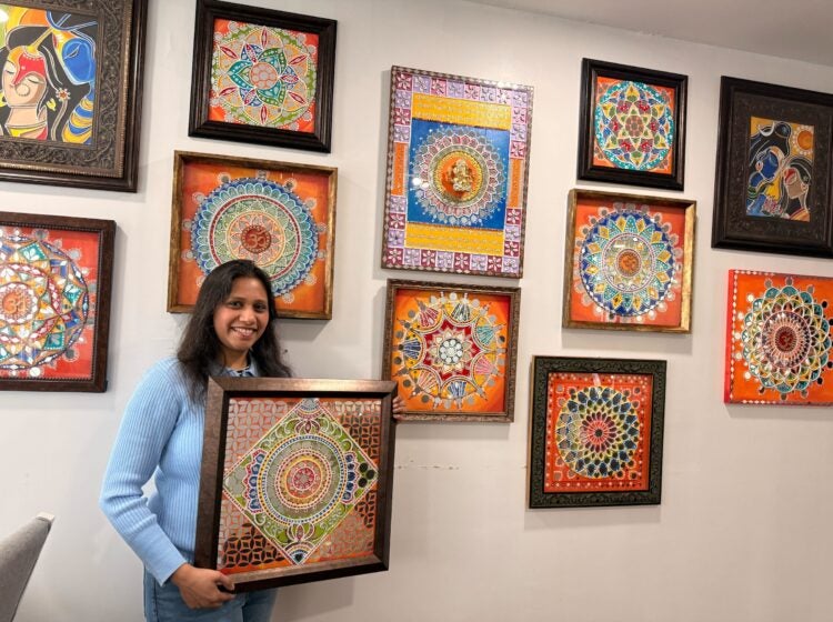 Apeksha Jain holding up a piece of her artwork