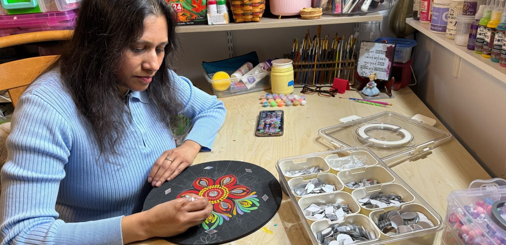 Apeksha Jain sitting at a table working on a piece of art