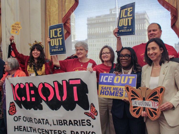 Kendra Brooks and Rue Landau pose with activists holding up signs saying 'ICE Out'