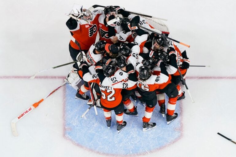 The Philadelphia Flyers gather around the net of goalie Dan Vladar, top left, as they celebrate after making the playoffs after an NHL hockey game against the Carolina Hurricanes, Monday, April 13, 2026, in Philadelphia.