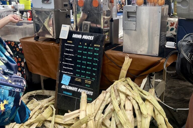 Used sugarcane falls onto the ground after being squeezed for juice at a juice vendor's stand