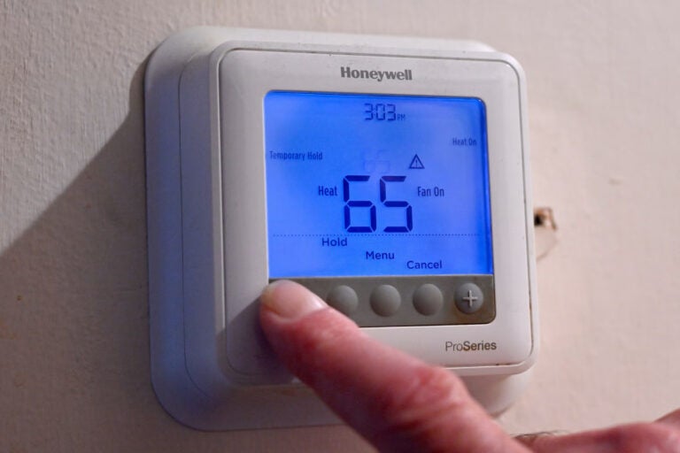 A person adjusts their thermostat