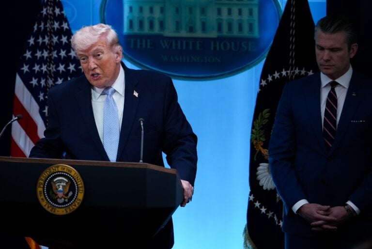 Donald Trump speaking at a podium, with Pete Hegseth standing beside him.