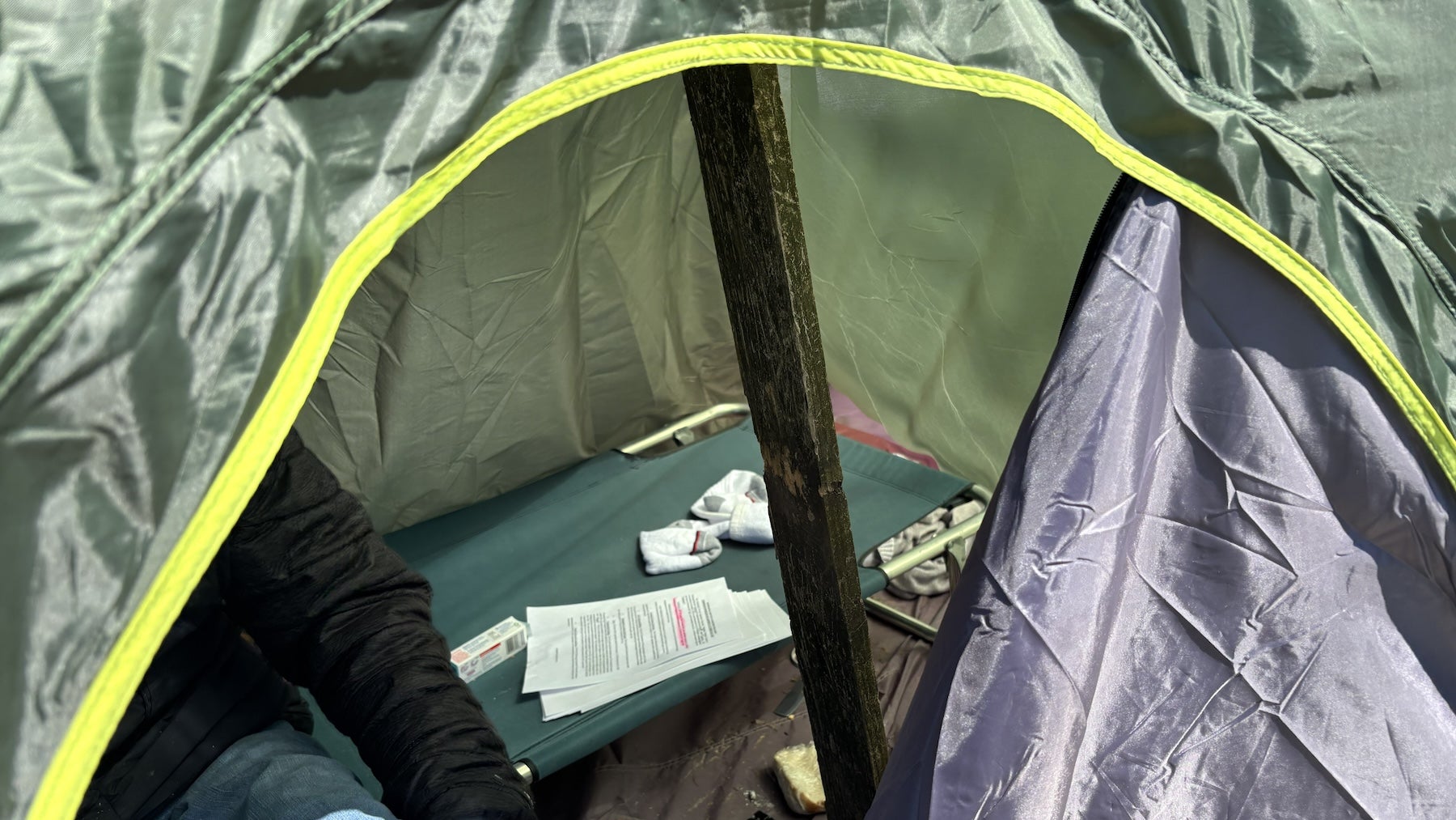 A wooden plank holds up a partially collapsed city-issued tent