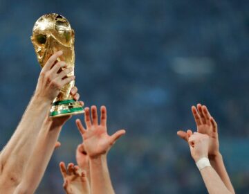 hands reaching up to touch the world cup trophy as one person holds it up