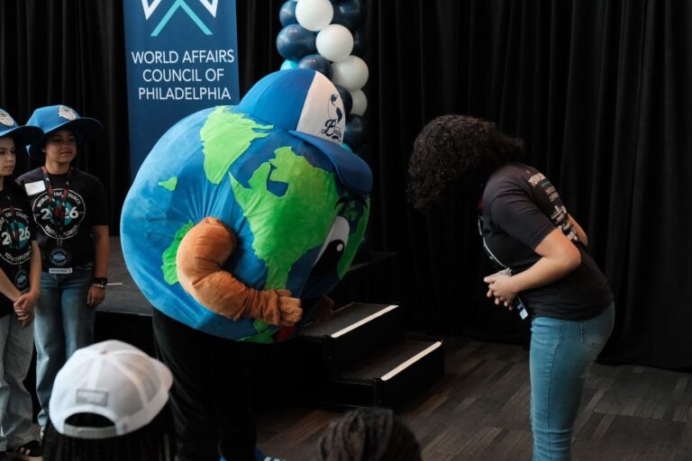 Amby and a youth diplomat demonstrate greetings