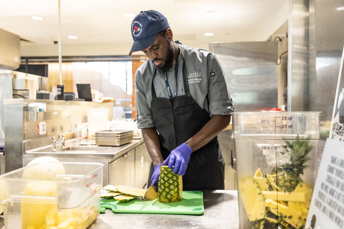 Mouhamed Mboup chops pineapple on Penn’s campus