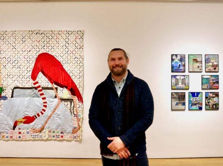 Jesse Krimes poses for photo in front of displayed quilts