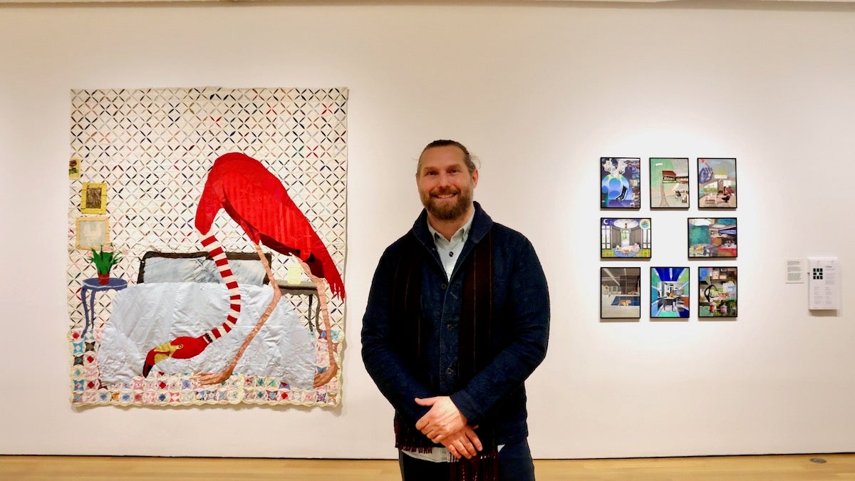 Jesse Krimes poses for photo in front of displayed quilts