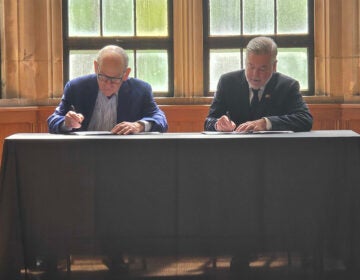 Joe Neubauer and Temple University President John Fry sign a scholarship agreement helping children of Philadelphia's first responders pay for college