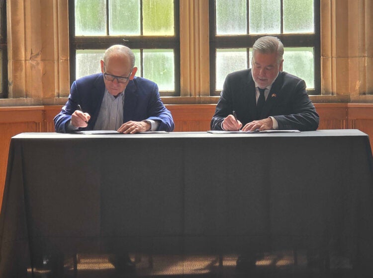 Joe Neubauer and Temple University President John Fry sign a scholarship agreement helping children of Philadelphia's first responders pay for college