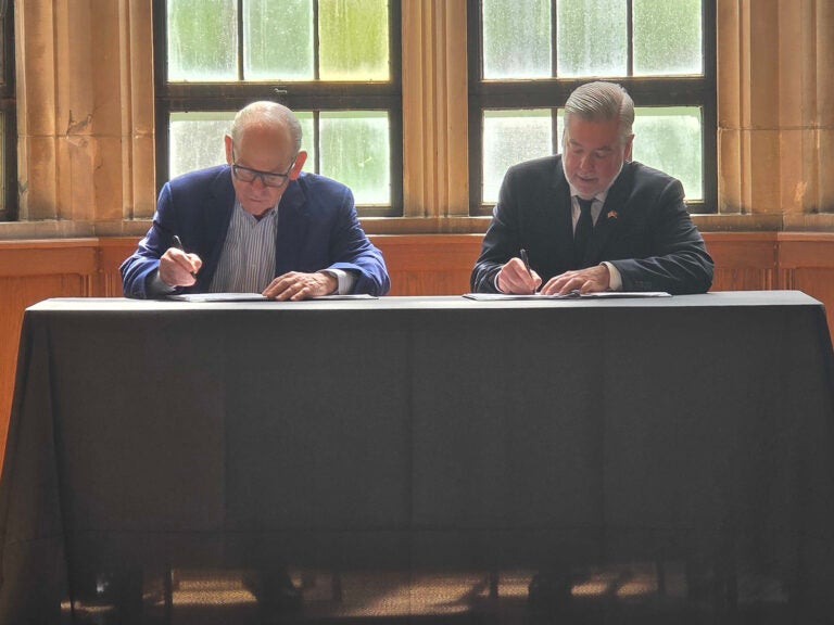 Joe Neubauer and Temple University President John Fry sign a scholarship agreement helping children of Philadelphia's first responders pay for college