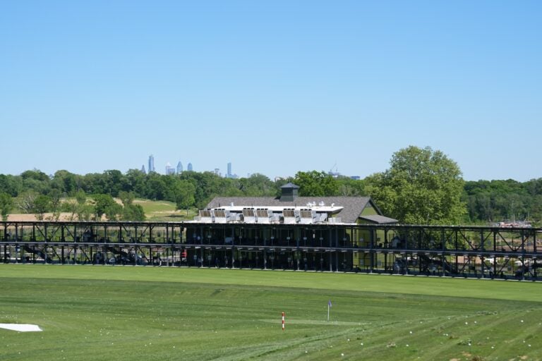 The Philadelphia skyline is seen above the driving range at the Cobbs Creek Golf Club